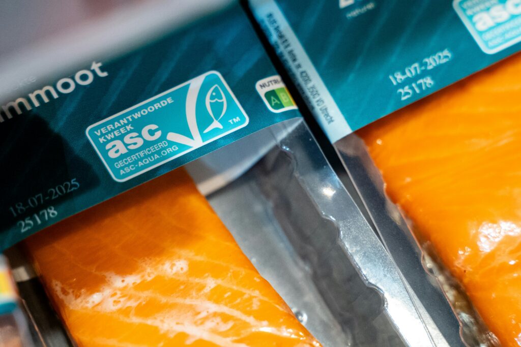 As embalagens inteligentes estão ganhando espaço na indústria de alimentos ao oferecer soluções voltadas à segurança alimentar, aumento da vida útil dos produtos, redução de desperdícios e melhor experiência para o consumidor. No segmento de proteínas, novas tecnologias vêm sendo aplicadas para preservar a qualidade dos alimentos durante toda a cadeia, da produção ao ponto de venda. Diferentemente das embalagens tradicionais, que atuam principalmente como barreira física, as embalagens inteligentes podem interagir com o alimento e o ambiente interno, controlando fatores como umidade, oxigênio e temperatura. Tetra Pak lança primeira embalagem cartonada para atum Embalagens inteligentes chegam ao mercado brasileiro A evolução das embalagens já aparece em produtos lançados no Brasil por grandes empresas do setor de alimentos. Na categoria de frangos, a Seara lançou uma linha de Cortes Resfriados com bandejas premium desenvolvidas para manter a embalagem mais seca. Segundo a marca, a solução contribui para preservar o frescor do produto, melhorar a apresentação no ponto de venda e ampliar a conveniência para o consumidor. Outro exemplo vem da Sadia, que apresentou uma lasanha de 350 g com embalagem produzida a partir de fibras de eucalipto. Desenvolvida em parceria com a Biona, empresa da Melhoramentos, a bandeja suporta temperaturas entre -40°C e 220°C e tem decomposição estimada em 75 dias, dependendo das condições ambientais. Tecnologia amplia segurança e conservação dos alimentos Entre os principais recursos das embalagens inteligentes está o controle de umidade. No caso das carnes, que possuem alto teor de água, a perda de líquidos durante o armazenamento pode impactar aparência, peso e qualidade. Para reduzir esse efeito, algumas embalagens utilizam materiais absorventes capazes de reter o excesso de umidade, ajudando também no controle de microrganismos associados à deterioração dos alimentos. Outra tecnologia aplicada é o uso de compostos antimicrobianos, que auxiliam na conservação ao reduzir o crescimento de bactérias e ampliar a vida útil dos produtos sem alterar características como sabor e textura. Controle de oxigênio aumenta vida útil dos produtos O controle do oxigênio é outro fator importante para a conservação. A presença do gás pode acelerar processos como oxidação das gorduras, alteração de cor e desenvolvimento de microrganismos. Por isso, sistemas que removem ou limitam o contato com oxigênio ajudam a manter as características do alimento por mais tempo. Nas embalagens a vácuo, por exemplo, a redução de oxigênio dificulta a multiplicação de fungos e bactérias aeróbias, permitindo maior tempo de conservação em comparação com alguns métodos tradicionais. Sensores e tecnologia digital transformam embalagens Além da conservação, as embalagens inteligentes também avançam com o uso de sensores capazes de acompanhar as condições do alimento ao longo da cadeia. Sadia lança bandeja biodegradável que se decompõe em 75 dias Algumas soluções identificam alterações relacionadas à deterioração, enquanto indicadores de tempo e temperatura mostram se o produto permaneceu dentro das condições adequadas durante transporte e armazenamento. A digitalização também ganha espaço nesse mercado. Tecnologias como QR Codes, realidade aumentada e sensores conectados permitem oferecer informações sobre origem, rastreabilidade, validade e formas de consumo. Sustentabilidade impulsiona novas embalagens A busca por menor impacto ambiental também influencia o desenvolvimento de novas soluções. Empresas do setor têm investido em materiais biodegradáveis, recicláveis e alternativas que buscam reduzir resíduos. Combinando conservação, segurança alimentar, sustentabilidade e tecnologia, as embalagens inteligentes ampliam sua presença e passam a representar uma das frentes de inovação da indústria de alimentos. Fonte: SA+ Foto de Paul Einerhand na Unsplash