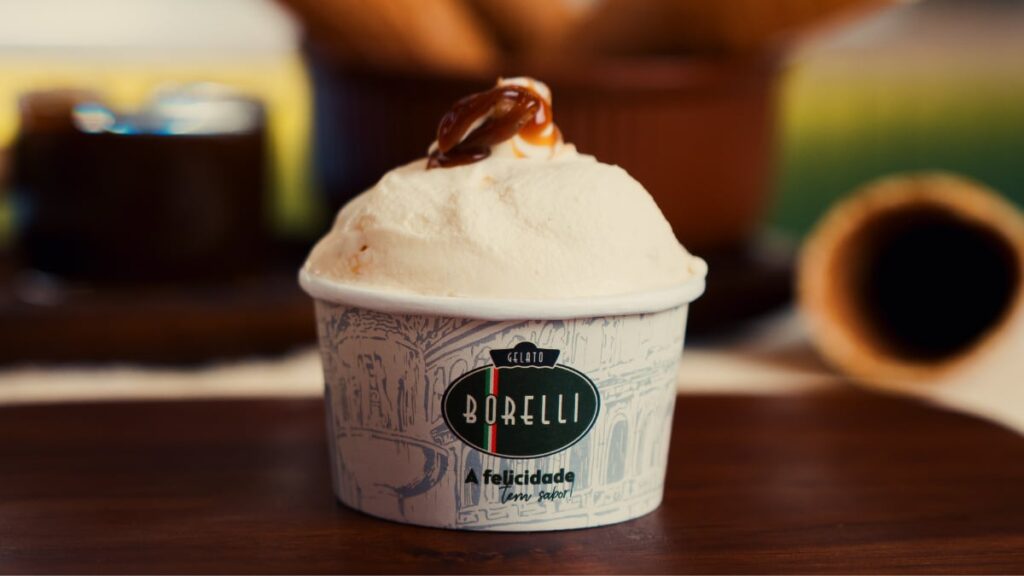 A Oro Bourbon é a nova aposta da Gelato Borelli para o Dia dos Pais. Desenvolvido em edição limitada, o sabor combina gelato de baunilha Bourbon, recheio e cobertura de variegato de whisky, além de caramelo crocante. O lançamento estará disponível entre os dias 6 e 16 de agosto, nas unidades participantes da rede e enquanto durarem os estoques. A novidade faz parte da estratégia da Borelli de ampliar seu portfólio com sabores sazonais, alinhados às principais datas do calendário. A iniciativa busca diversificar as ocasiões de consumo e estimular visitas às lojas em períodos comemorativos. Oro Bourbon reforça estratégia de lançamentos sazonais Com o Oro Bourbon, a Borelli dá sequência ao investimento em edições limitadas para manter o portfólio em constante renovação. A proposta é oferecer sabores exclusivos em momentos específicos do ano, criando novas experiências para os consumidores. Segundo a empresa, esse modelo também fortalece a presença da marca em datas de grande apelo comercial, como o Dia dos Pais, ao associar os produtos a momentos de celebração. Receita combina baunilha Bourbon, whisky e caramelo O Oro Bourbon reúne gelato de baunilha Bourbon, recheio e cobertura de variegato de whisky e finalização com caramelo crocante. A combinação aposta em sabores tradicionalmente associados à sobremesa para compor uma edição especial voltada à data comemorativa. Nestlé relança Snow Churros em edição limitada De acordo com Tony Miranda, CEO da Borelli, os lançamentos sazonais fazem parte da estratégia da rede para acompanhar as mudanças no comportamento do consumidor e manter o portfólio atualizado ao longo do ano. "Na Borelli, entendemos que inovação também está na capacidade de acompanhar a evolução do comportamento do consumidor e criar experiências relevantes ao longo do ano. Os sabores sazonais fazem parte dessa estratégia porque mantêm o portfólio dinâmico e reforçam nossa conexão com diferentes ocasiões de consumo." Disponibilidade O Oro Bourbon estará disponível entre 6 e 16 de agosto nas unidades participantes da Gelato Borelli, em edição limitada e enquanto durarem os estoques. Fonte: GKPB Imagem: GKPB / Reprodução
